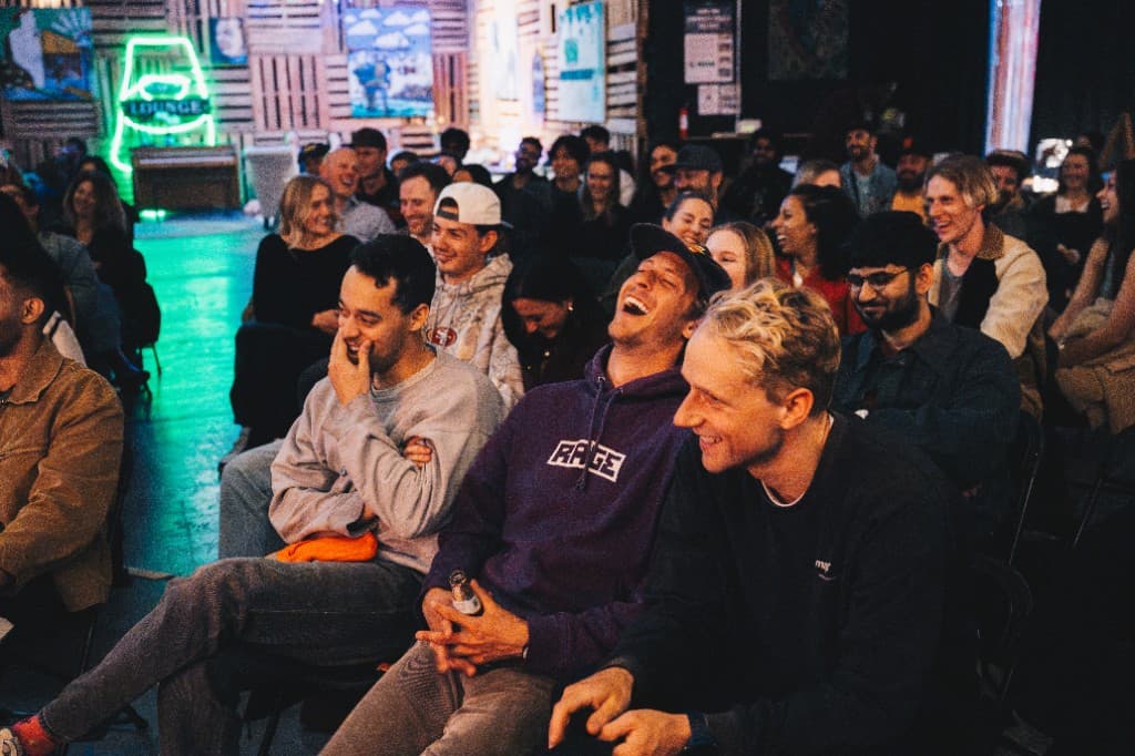 Audience laughing at The Comedy Run Club in a dimly lit lounge